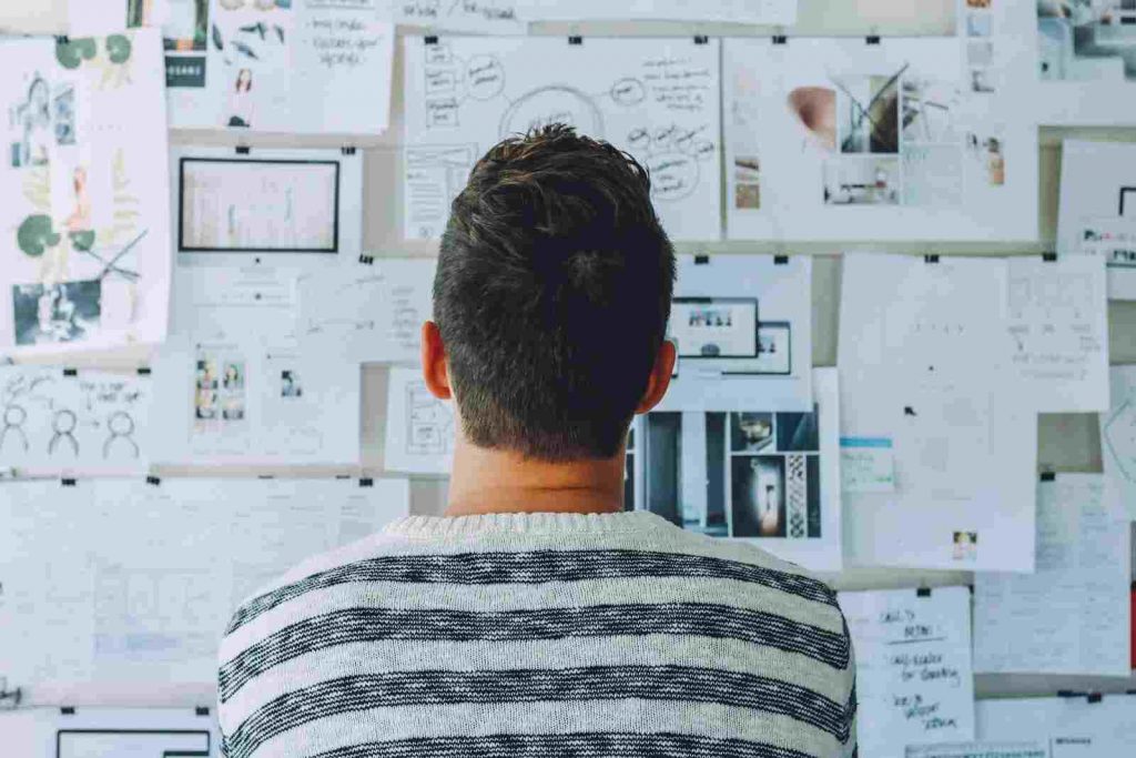 a ux designer looking on a wall which consist of ux designs clipped
